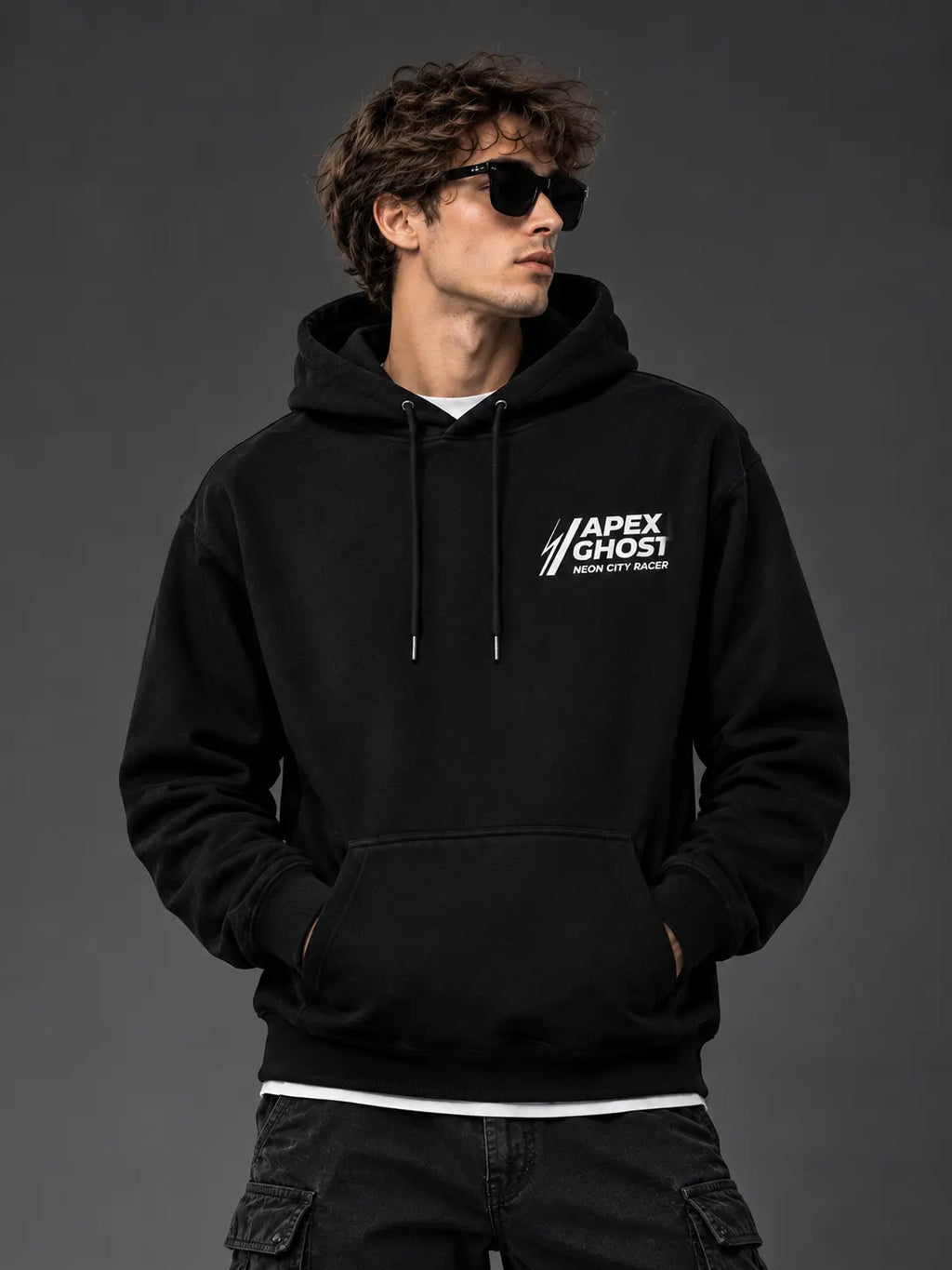 Man wearing black Apex Ghost hoodie with front chest logo on studio background