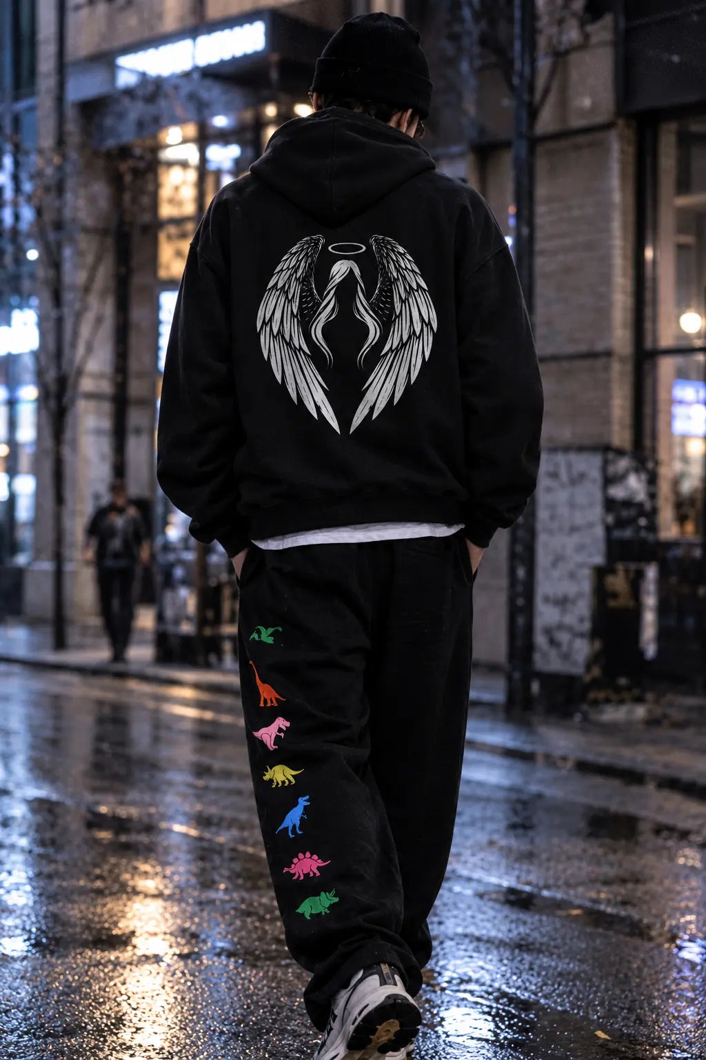 Back view of streetwear model wearing fallen angel hoodie and black fleece jogger sweatpants with colorful dinosaur print